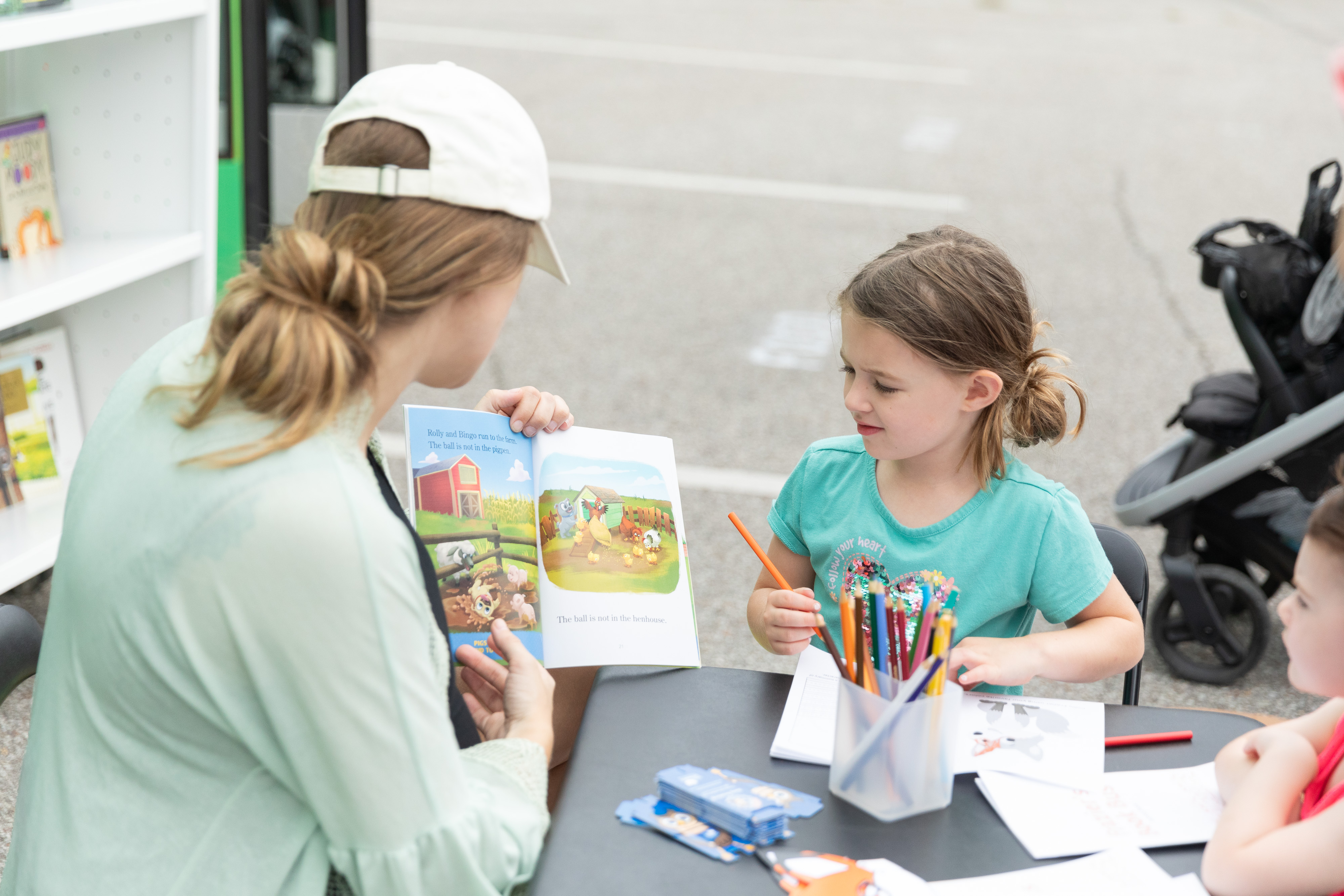 Two young girls are listening to their mother as she reads a book.
